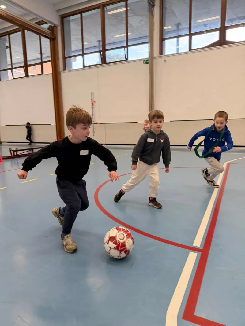 Jongens rennen achter de bal in de sporthal tijdens een kinderfeestje van Bougez