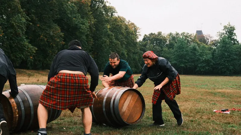 Deelnemers in kilt rollen houten tonnen tijdens de Highland Games van Bougez