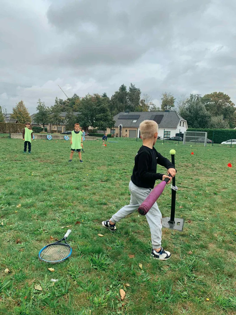 Jongen slaat de bal weg met een slaghout tijdens een kinderfeestje van Bougez
