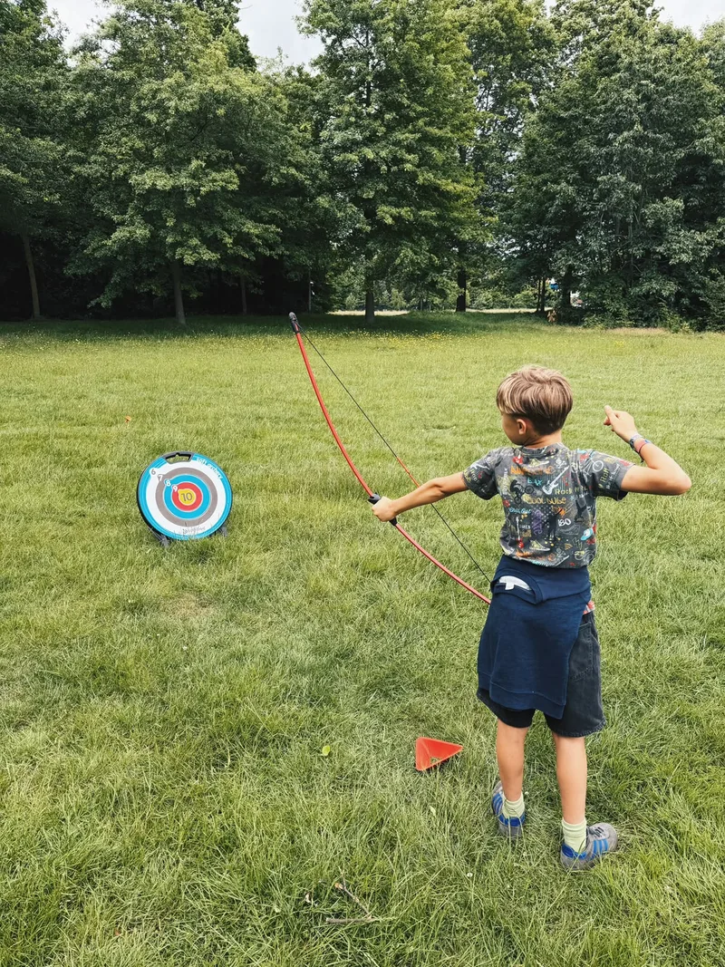 Jongen mikt met pijl en boog op een doel in het park tijdens een kinderfeestje van Bougez