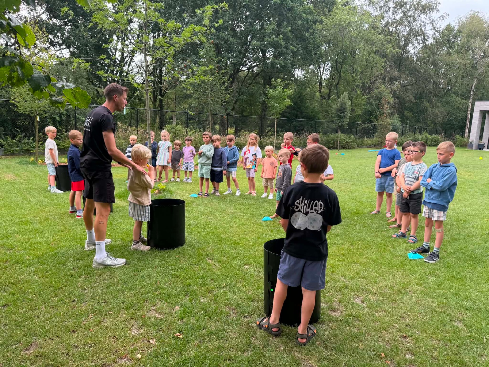 Niels geeft uitleg aan een groep kinderen tijdens een feestje in het gras