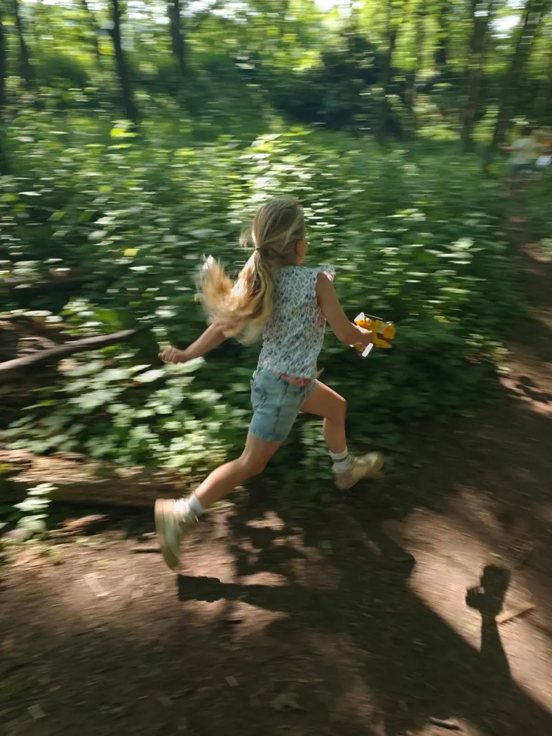 Meisje rent door het bos tijdens een bosspel van Bougez