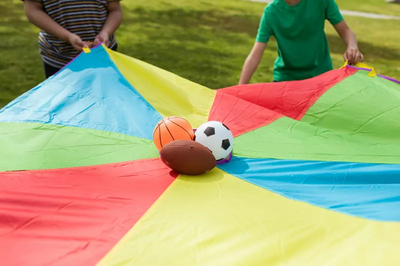 Kinderen gooien ballen omhoog met de parachute op een kinderfeestje van Bougez