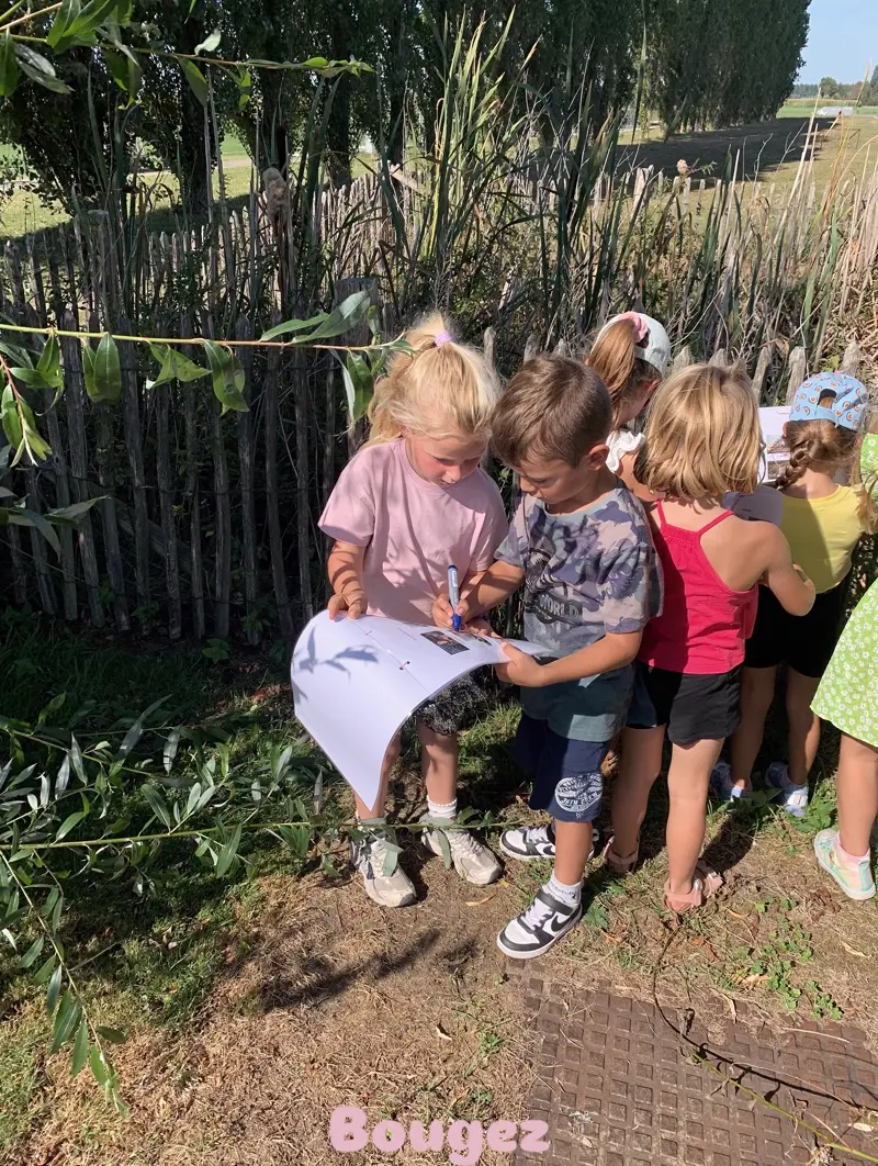 Kinderen bekijken samen hun opdrachtenkaart in het groen tijdens een spel van Bougez