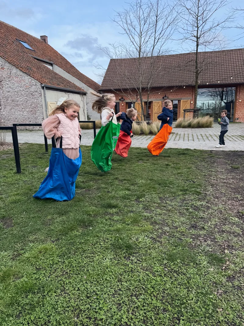 Kinderen springen lachend in de zak tijdens een zakloop op een kinderfeestje van Bougez