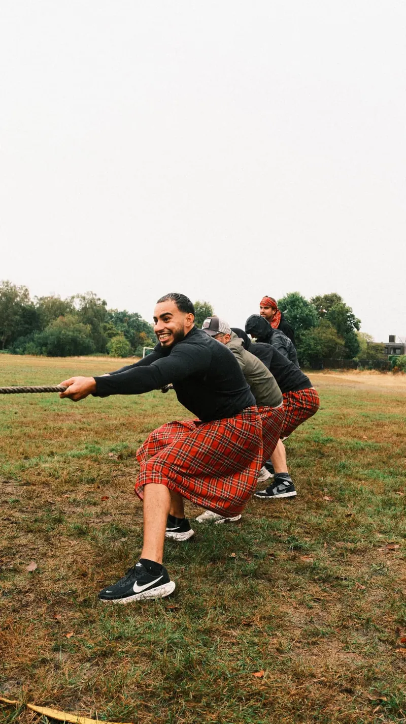 Deelnemer lacht terwijl zijn team aan het touw trekt tijdens de Highland Games van Bougez