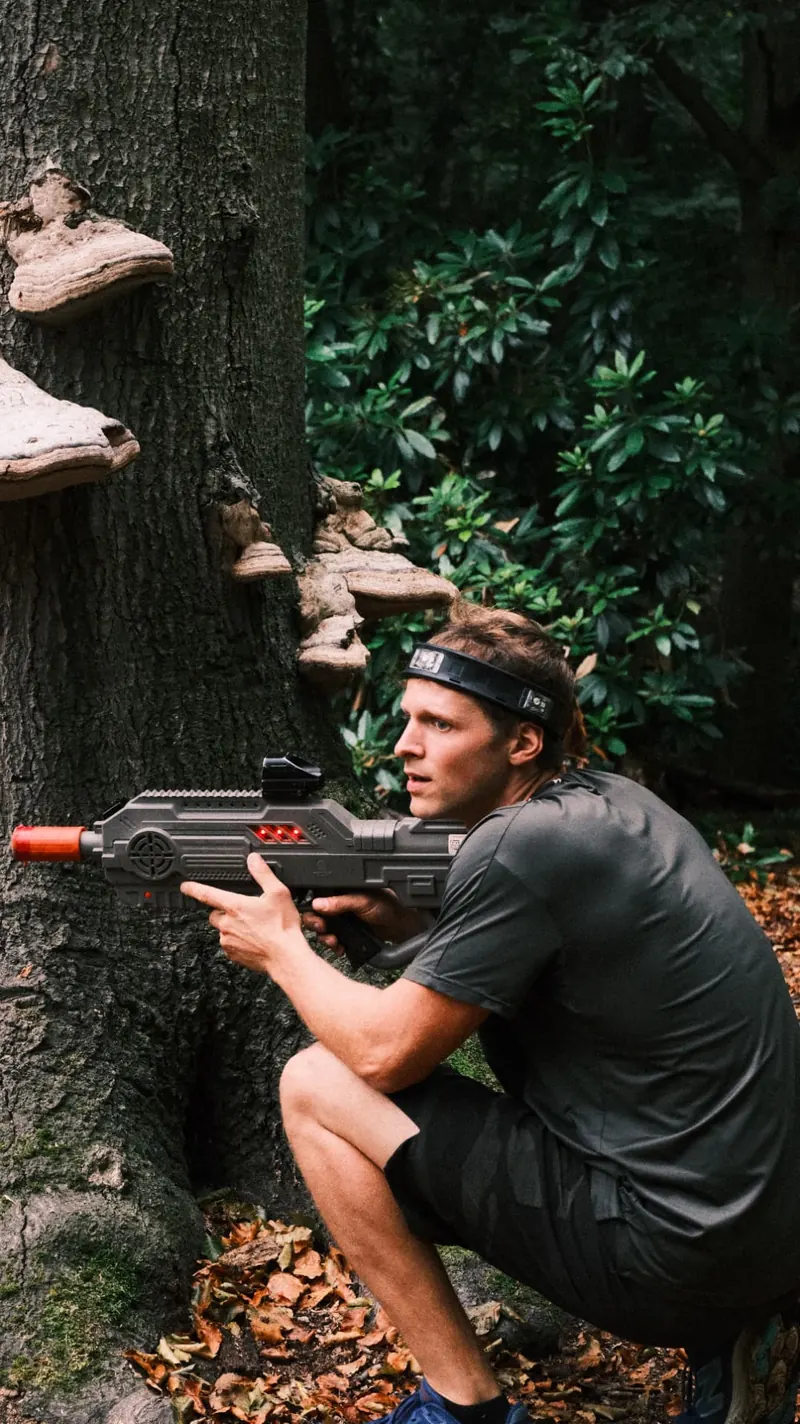 Deelnemer zoekt dekking achter een boom tijdens een lasershoot van Bougez