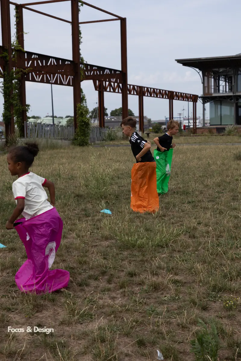 Kinderen huppen in kleurige zakken tijdens een zakloop op het gras bij een kinderfeestje van Bougez