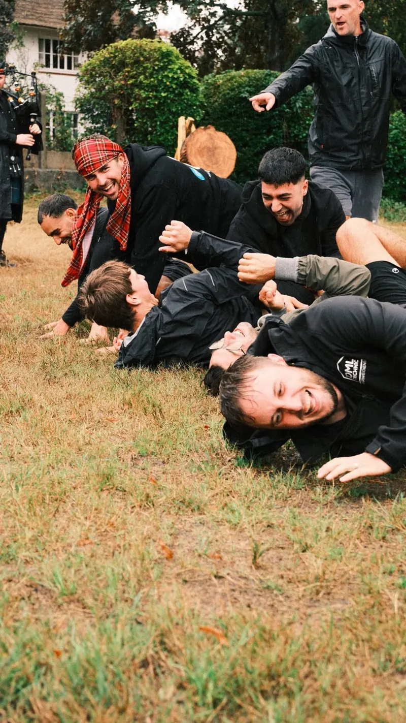 Deelnemers liggen lachend in het gras na een opdracht tijdens de Highland Games van Bougez